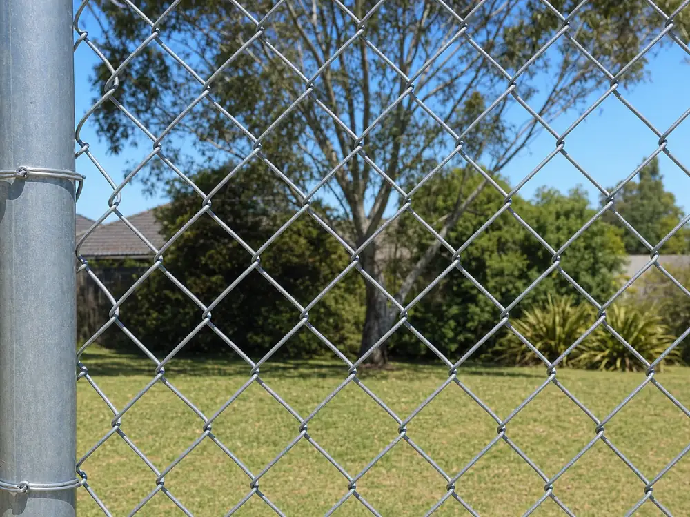 Close view of galvanised cyclone fence mesh tied to a steel post in a Melbourne backyard
