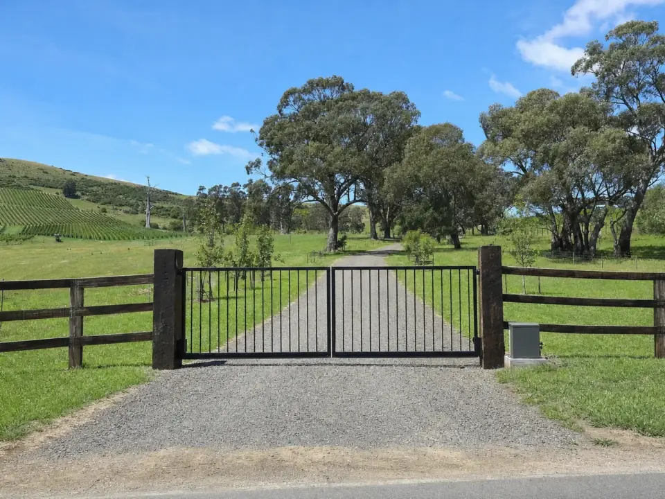 Black steel double entrance gates between heavy timber posts on a rural property outside Melbourne