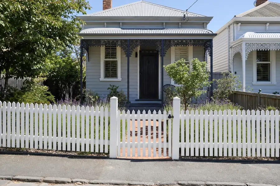 White timber picket pedestrian gate on the brick path of a Victorian weatherboard cottage in inner Melbourne